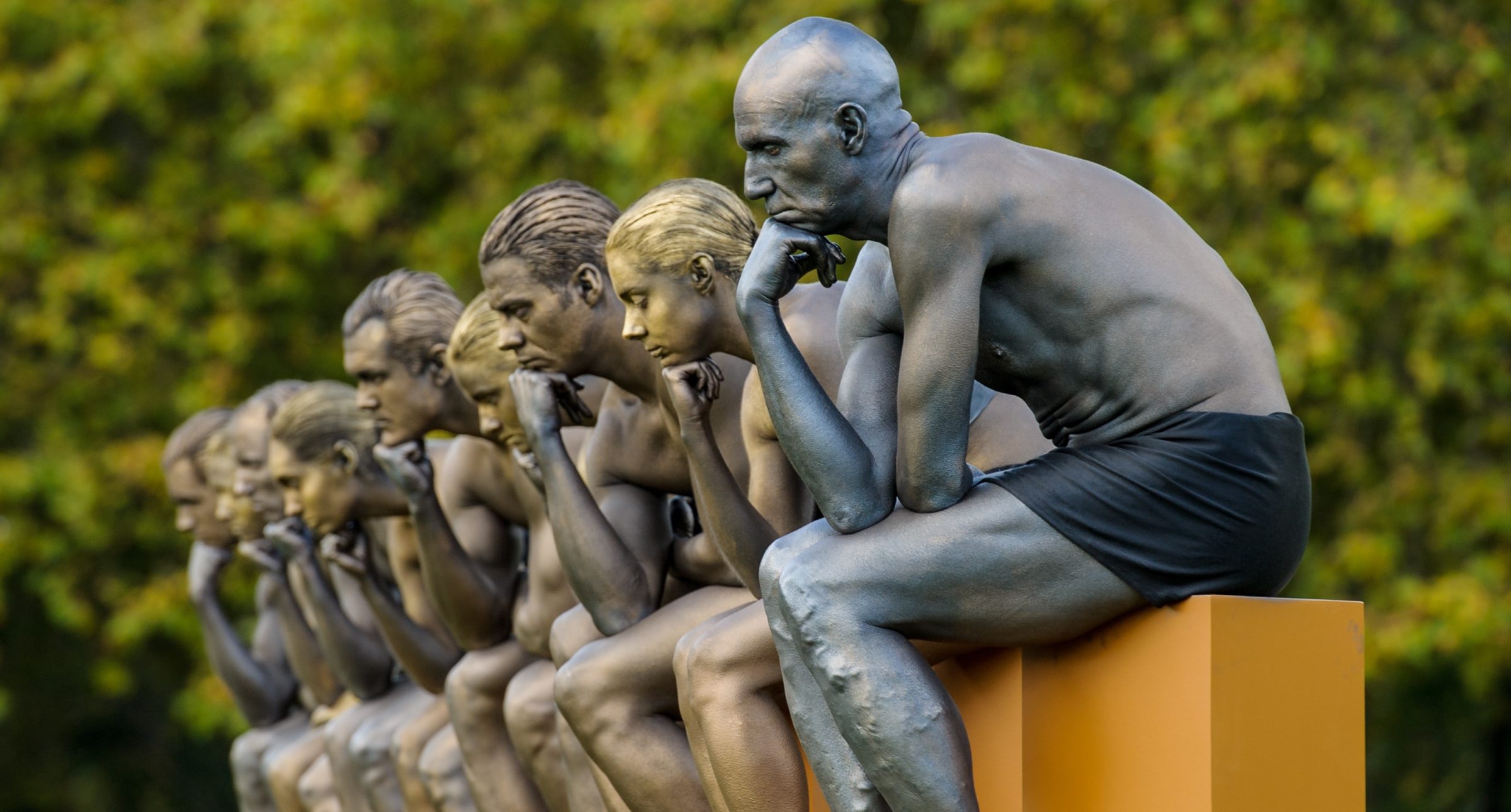 Nine models pose as Rodin's The Thinker